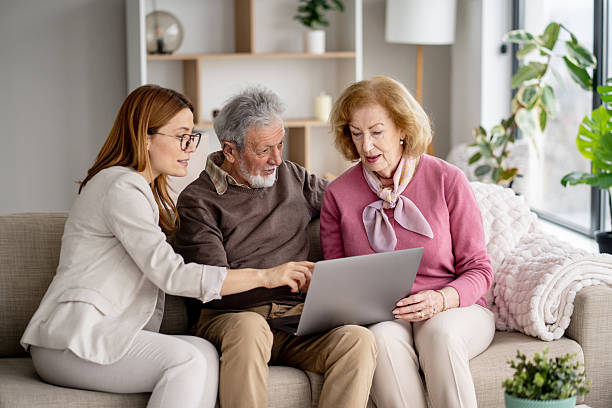 A woman assists an elderly couple as they explore a laptop